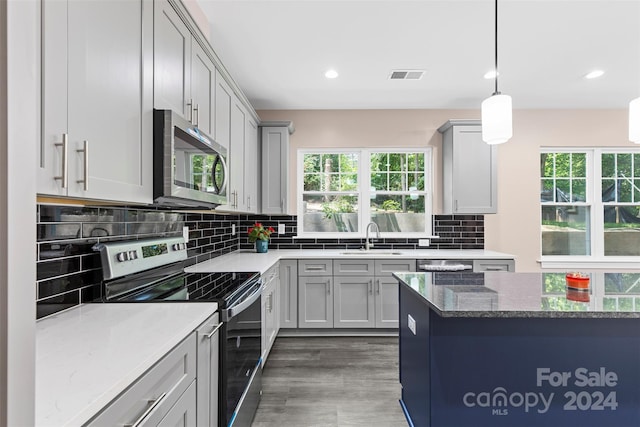 kitchen with wood-type flooring, a wealth of natural light, tasteful backsplash, and stainless steel appliances