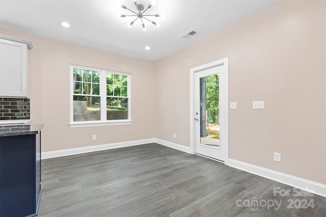 unfurnished dining area with a notable chandelier and dark wood-type flooring