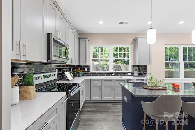 kitchen featuring plenty of natural light, decorative backsplash, dark wood-type flooring, and stainless steel appliances