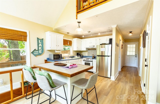 kitchen featuring tile countertops, white cabinetry, stainless steel appliances, decorative light fixtures, and light wood-type flooring