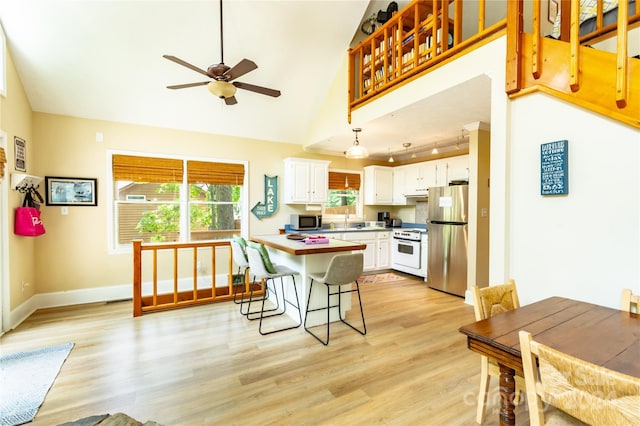 kitchen featuring ceiling fan, white cabinetry, light wood-type flooring, appliances with stainless steel finishes, and a breakfast bar area