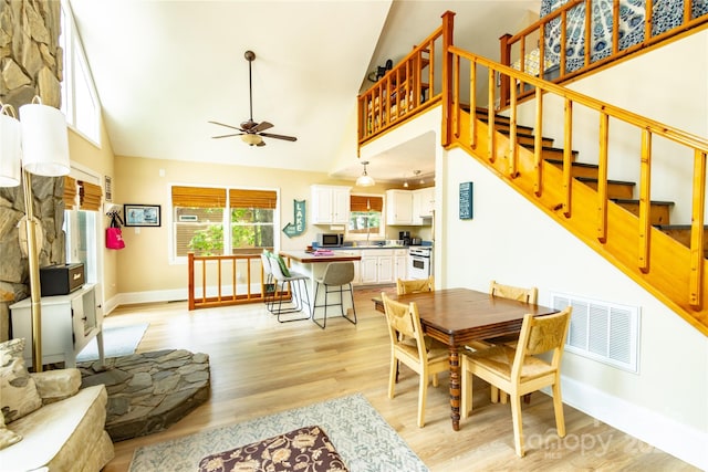 dining room featuring ceiling fan, light hardwood / wood-style floors, and high vaulted ceiling