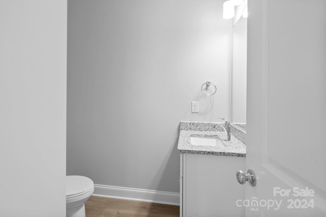 bathroom with hardwood / wood-style flooring, toilet, and vanity