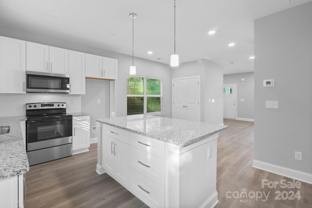 kitchen featuring decorative backsplash, stainless steel appliances, wood-type flooring, and a kitchen island