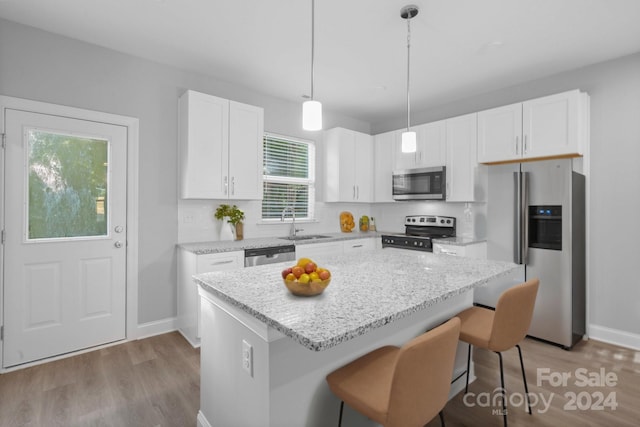 kitchen featuring white cabinetry, stainless steel appliances, light hardwood / wood-style floors, and a kitchen island