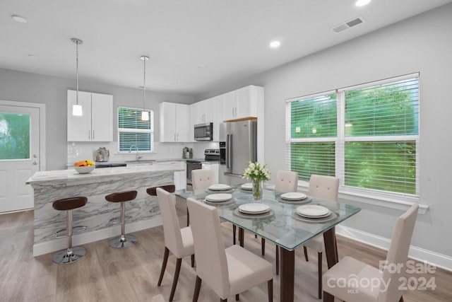 dining room featuring sink, light hardwood / wood-style flooring, and a healthy amount of sunlight