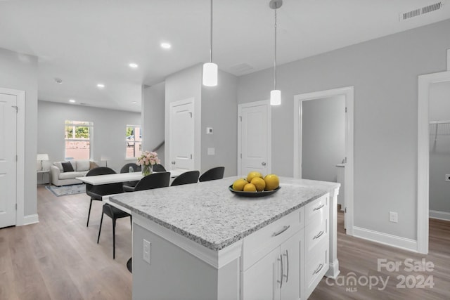 kitchen featuring light hardwood / wood-style flooring, a center island, white cabinets, and light stone counters