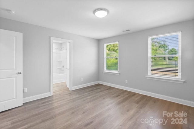 unfurnished bedroom featuring a closet, hardwood / wood-style flooring, and a walk in closet