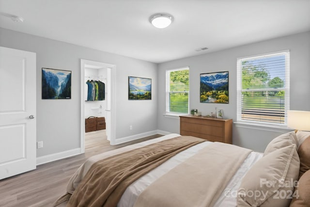 bedroom with a closet, hardwood / wood-style flooring, and a walk in closet