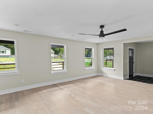 empty room with light hardwood / wood-style floors, plenty of natural light, and ceiling fan