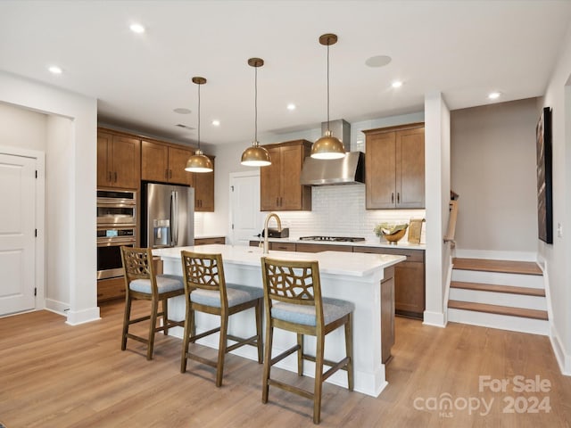 kitchen featuring an island with sink, stainless steel appliances, backsplash, a kitchen breakfast bar, and pendant lighting