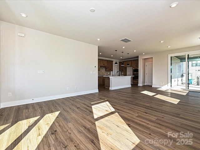 unfurnished living room featuring recessed lighting, visible vents, dark wood-style flooring, and a sink