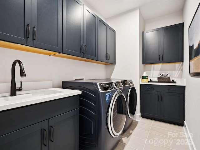 laundry room with baseboards, light tile patterned flooring, cabinet space, a sink, and washing machine and dryer