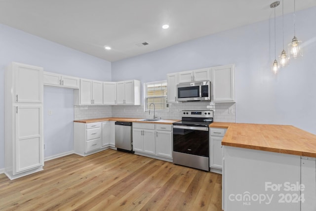 kitchen with pendant lighting, light hardwood / wood-style flooring, white cabinetry, stainless steel appliances, and wood counters