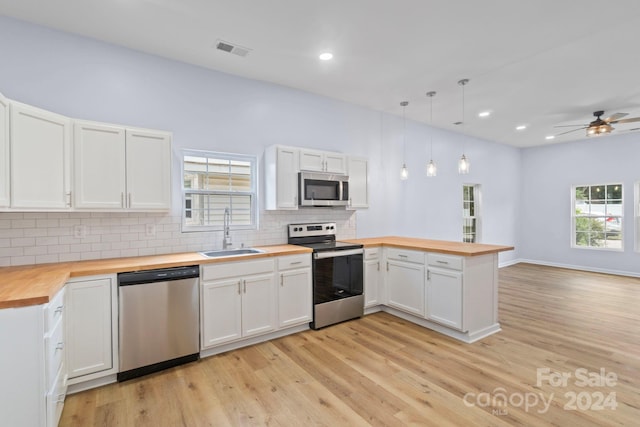 kitchen featuring sink, butcher block counters, kitchen peninsula, stainless steel appliances, and ceiling fan