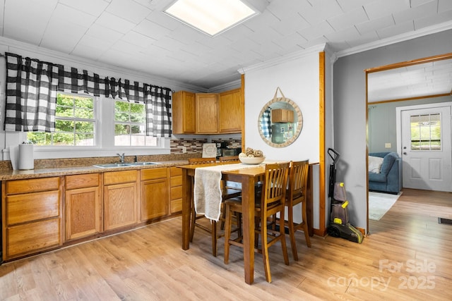 kitchen with crown molding, sink, and light wood-type flooring