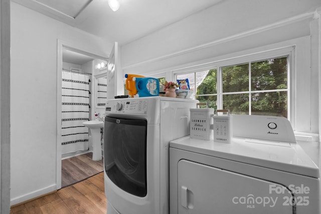 clothes washing area with washer and clothes dryer and light hardwood / wood-style flooring