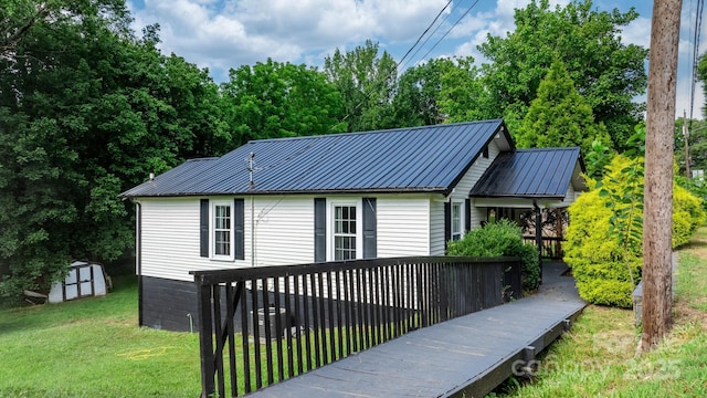 exterior space featuring a wooden deck, a front lawn, and a storage unit