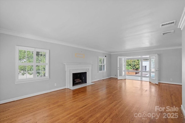 unfurnished living room with light hardwood / wood-style flooring, plenty of natural light, ornamental molding, and a premium fireplace