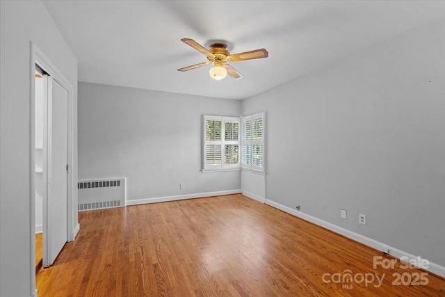 unfurnished bedroom with ceiling fan, radiator heating unit, and light hardwood / wood-style floors