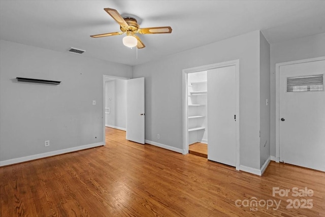 unfurnished bedroom featuring ceiling fan, a spacious closet, a closet, and light hardwood / wood-style flooring