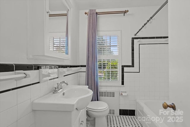 bathroom featuring radiator, tile walls, tile patterned flooring, vanity, and toilet