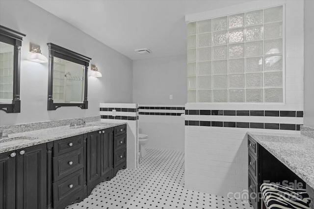 bathroom with tile walls, vanity, tile patterned flooring, and toilet