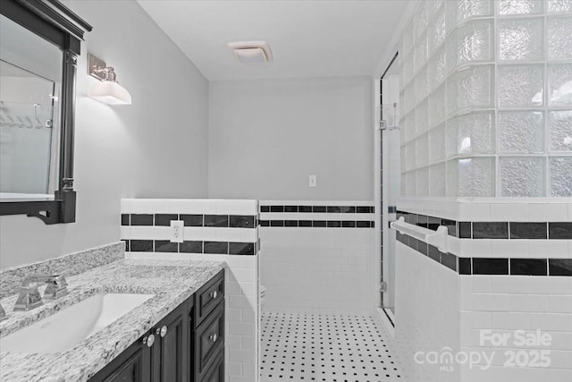 bathroom with tile walls, an enclosed shower, and vanity