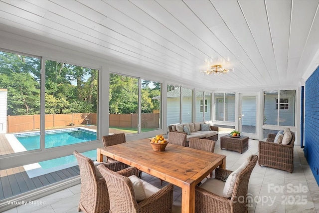 sunroom / solarium featuring a healthy amount of sunlight and wooden ceiling