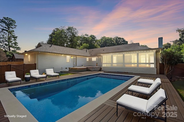 pool at dusk with a wooden deck