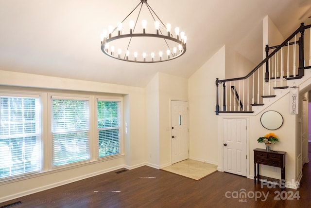 entryway with vaulted ceiling, an inviting chandelier, and hardwood / wood-style flooring