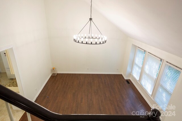 unfurnished dining area with lofted ceiling, a chandelier, and dark hardwood / wood-style flooring