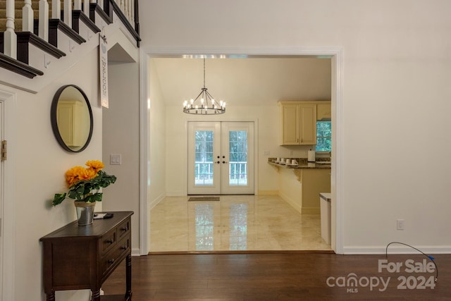 entrance foyer with french doors, hardwood / wood-style floors, and an inviting chandelier