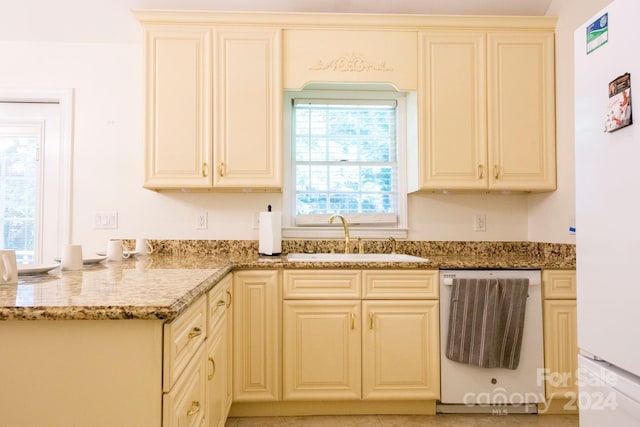 kitchen with white appliances, light stone counters, sink, and cream cabinetry