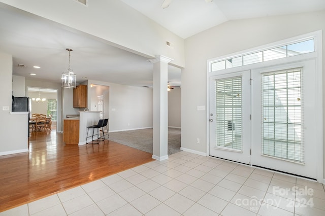 interior space with lofted ceiling, ceiling fan with notable chandelier, light tile patterned floors, and a wealth of natural light