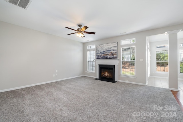 unfurnished living room with light colored carpet, decorative columns, and ceiling fan