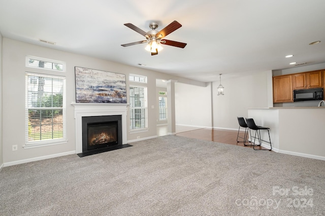 unfurnished living room with ceiling fan and carpet