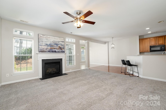 unfurnished living room featuring carpet and ceiling fan