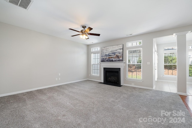 unfurnished living room featuring light carpet, ornate columns, and ceiling fan