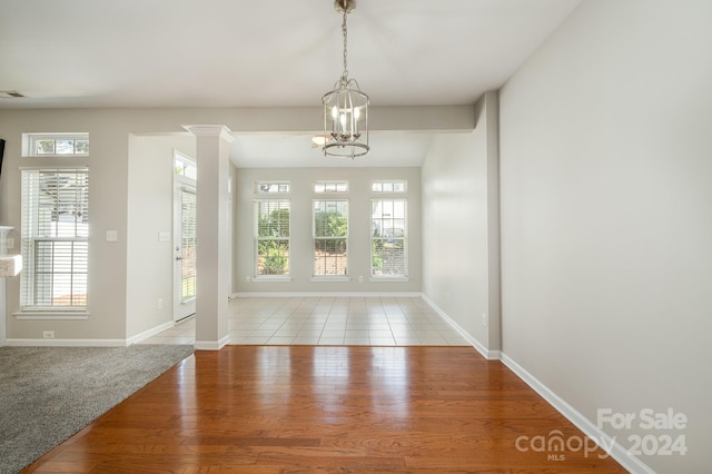 carpeted foyer with ornate columns and an inviting chandelier