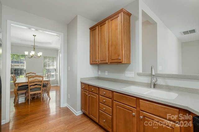 kitchen featuring light hardwood / wood-style flooring, sink, a notable chandelier, and hanging light fixtures