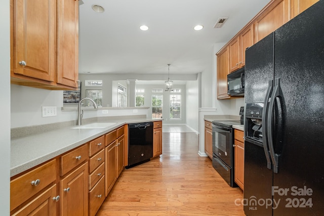 kitchen with an inviting chandelier, light hardwood / wood-style flooring, sink, black appliances, and pendant lighting