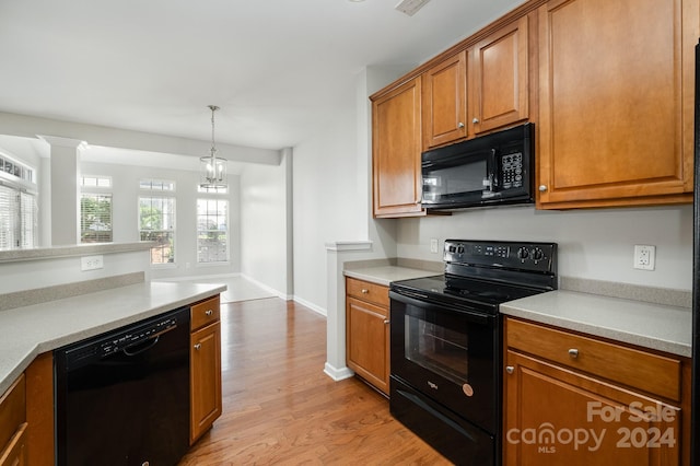 kitchen with decorative light fixtures, black appliances, decorative columns, a chandelier, and light wood-type flooring