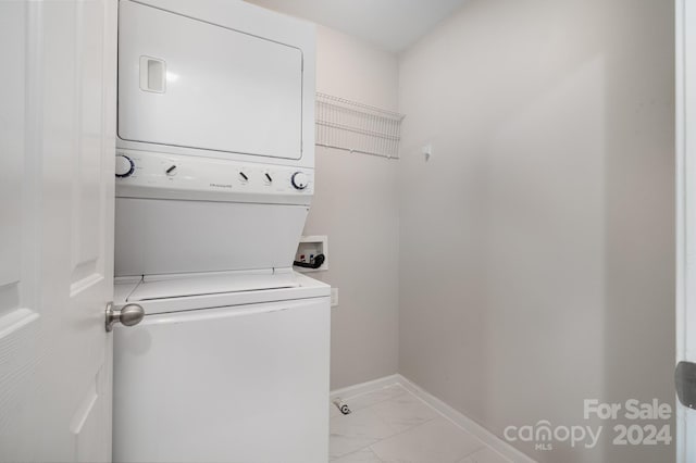 clothes washing area featuring light tile patterned floors and stacked washer / drying machine