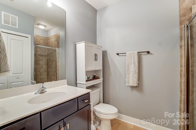 bathroom with hardwood / wood-style flooring, a shower with door, toilet, and vanity