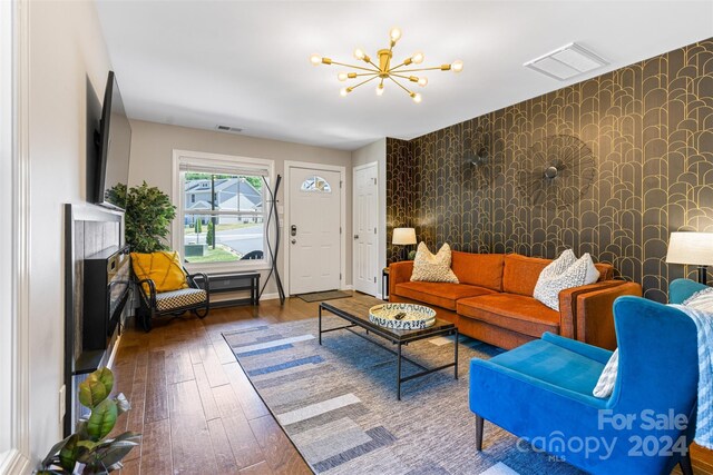 living room featuring a fireplace, wood-type flooring, and an inviting chandelier