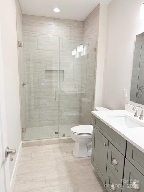 bathroom featuring toilet, vanity, and an enclosed shower