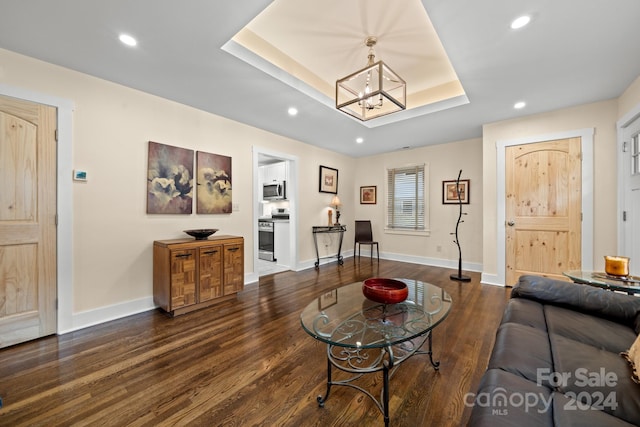 living room with a raised ceiling, dark hardwood / wood-style floors, and a notable chandelier