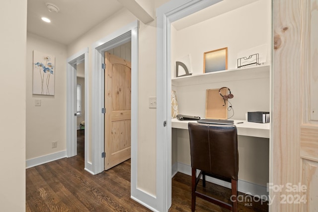 office with dark hardwood / wood-style flooring and built in desk