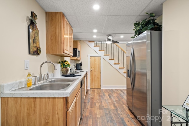 kitchen with a paneled ceiling, appliances with stainless steel finishes, sink, and hardwood / wood-style flooring